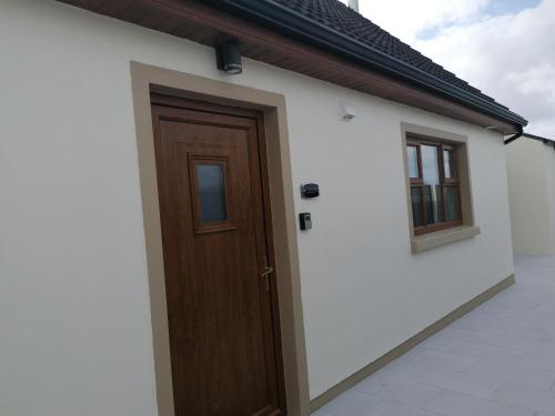 a house with a wooden door and two windows at Atlantic way Apartment 1 in Breaghwy
