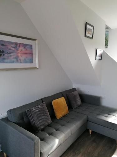 a living room with a gray couch with yellow pillows at Atlantic way Apartment 1 in Breaghwy