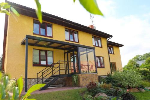 a yellow house with a staircase in front of it at Greenland Apartments in Cēsis