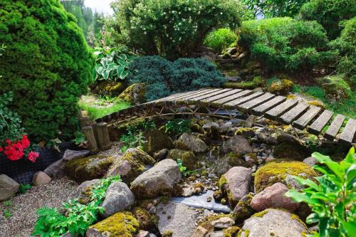 a garden with a wooden bridge and some rocks at Greenland Apartments in Cēsis