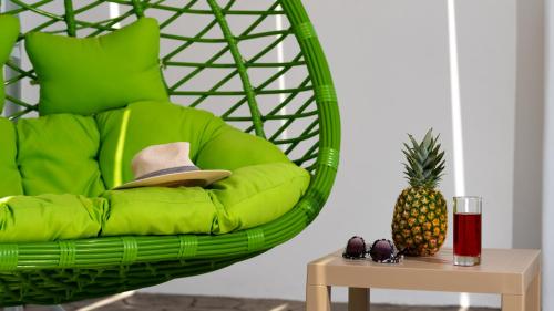 a green chair with a hat and a table at Villa Echedra in Vlychada