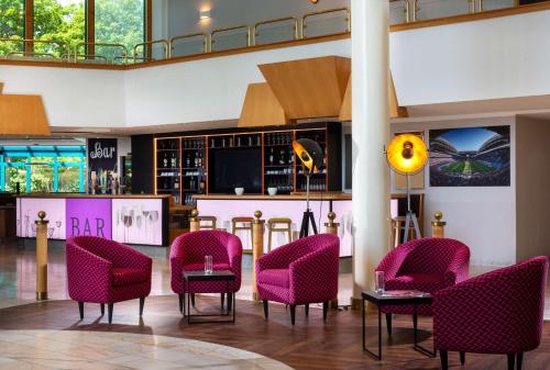 eine Lobby mit rosa Stühlen und einer Bar in der Unterkunft Best Western Parkhotel Brehna-Halle in Brehna