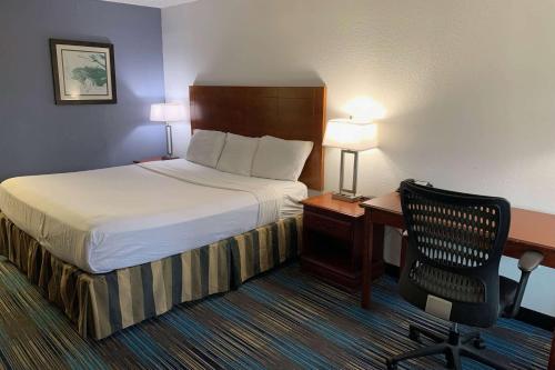 a hotel room with a bed and a desk and a chair at Travelodge by Wyndham Mobile AL in Mobile