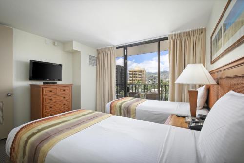 Habitación de hotel con 2 camas y ventana grande. en Aston Waikiki Sunset, en Honolulu