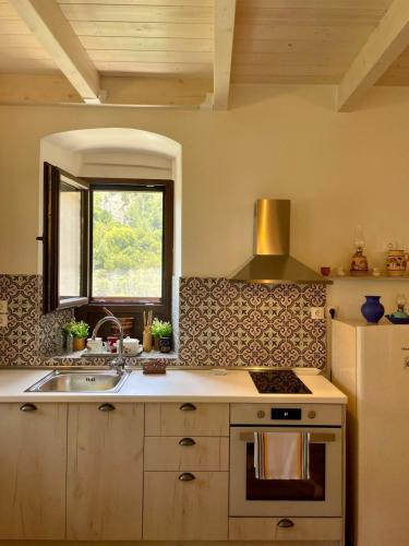 a kitchen with a sink and a stove and a window at Rodanthe's Guest House in Stemnitsa