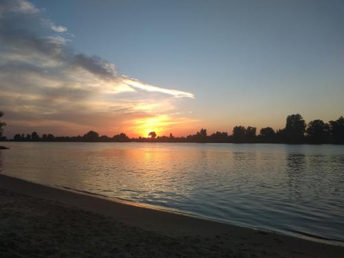 a sunset over a body of water with the sun setting at The Two Branches in 't Waal