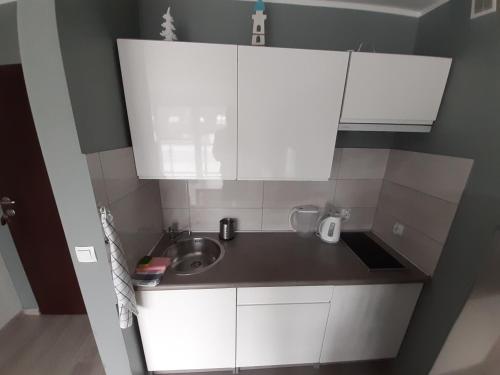 uma pequena cozinha com armários brancos e um lavatório em Cichy port Darlowo em Darłowo