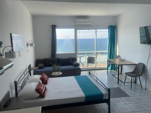 a bedroom with a bed and a living room with a view of the ocean at Julies Studios in Chania Town