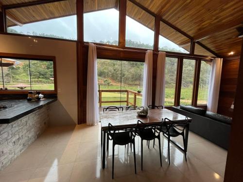 a dining room with a table and chairs and windows at Rancho Nosso Lago in Domingos Martins