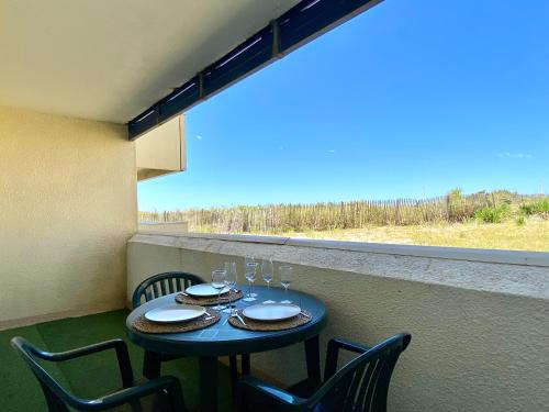 une table avec des chaises et des verres à vin sur un balcon dans l'établissement Appartement Cosy en Bord d'Océan, à Lacanau