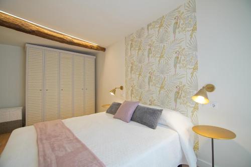 a bedroom with a white bed and a wall at Piso Turqueta, Céntrico Casco Antiguo Castro Urdiales in Castro-Urdiales