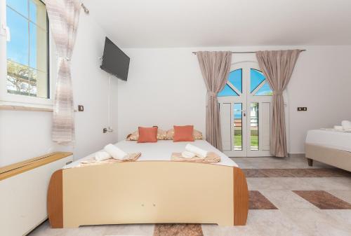a bedroom with a large bed and two windows at Villa Božica - sea view stone villa with free parking in Makarska