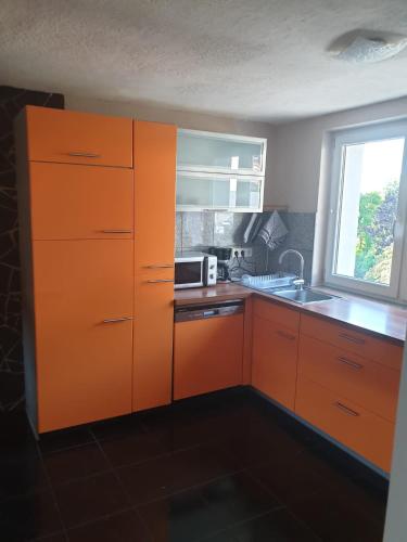 an orange kitchen with a sink and a microwave at Apartment da Luiz Salvatore in Wurmlingen