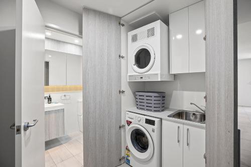 a kitchen with white cabinets and a washer and dryer at Rockpool 2 Sawtell Beach - Just steps to Restaurants and 2 min Stroll to Beach! in Sawtell