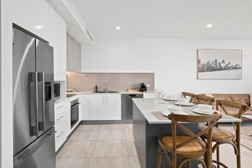 a kitchen with a table with chairs and a refrigerator at Rockpool 2 Sawtell Beach - Just steps to Restaurants and 2 min Stroll to Beach! in Sawtell