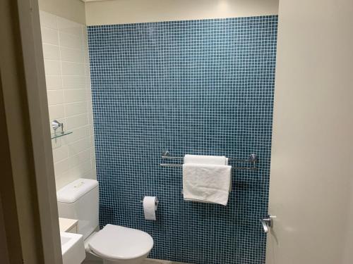 a bathroom with a toilet and a blue tiled wall at 40 William Street Apartments in Port Macquarie