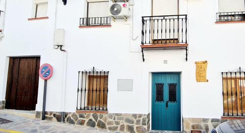 a white building with blue doors and windows at Preciosa casa de pueblo entre Ronda y Setenil La Posada de Catalina in Montecorto
