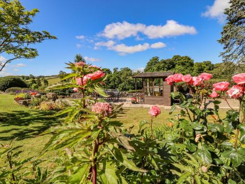 a garden with pink flowers and a small cabin at 1 Bridge End & Garden in Grassington