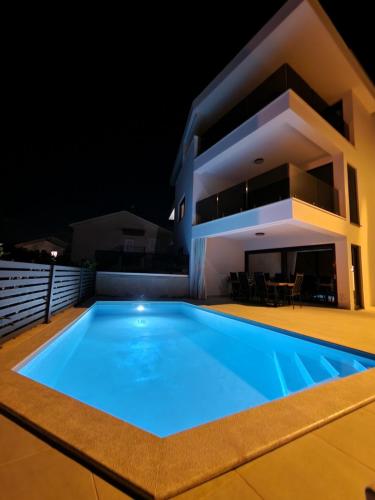 a villa with a swimming pool at night at Luxury apartment Marco Polo with a private swimming pool with salt sea water in Punat