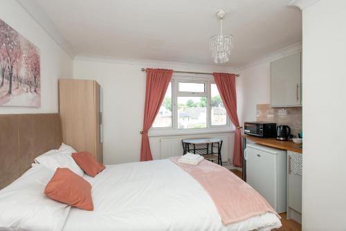 a bedroom with a large white bed with orange pillows at Modern Studio Apartments in Bromley, Greater London near Tesco and Sundridge Park Station in Bromley
