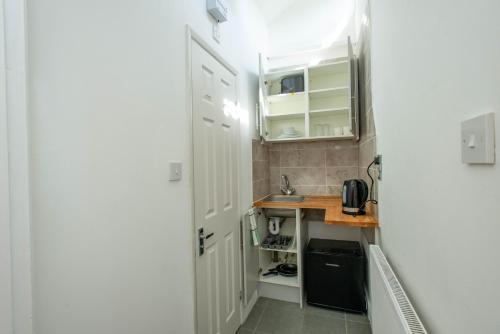 a small kitchen with white cabinets and a sink at Modern Studio Apartments in Bromley, Greater London near Tesco and Sundridge Park Station in Bromley