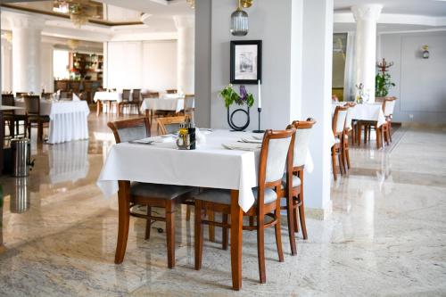 a dining room with a white table and chairs at Hotel Atena Wedding, Business & Spa in Ciechanów