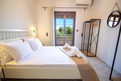 a bedroom with a large white bed with a window at Palmeira Sea & City in Preveza