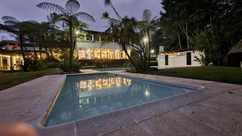 a swimming pool in front of a house at night at Posada Montaña del Quetzal in Cobán