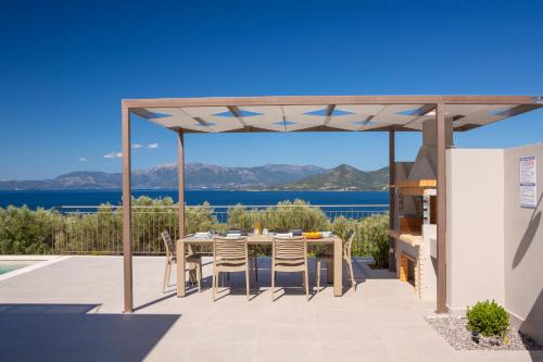 pérgola en un patio con mesa y sillas en Ionian Sunshine Villas, en Paleros