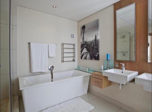 a bathroom with a large tub and a sink at The Pearls of Umhlanga - Ocean view Apartments in Durban