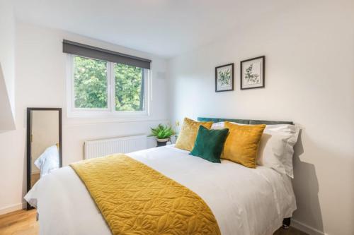 1 dormitorio con 1 cama con almohadas amarillas y verdes en Apartments in Brixton next door to Brockwell Park, en Londres