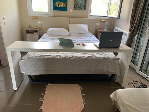a bedroom with a bed with a desk and a laptop on it at Villa Sorina Kefalonia in Svoronata