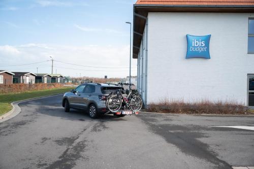 a car parked next to a building with bikes on it at ibis budget Oostende Airport in Ostend
