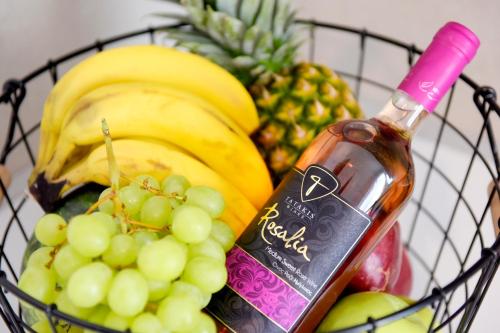 Naya Ixia Rhodes Apartment في إيكسيا: سلة من الفواكه مع زجاجة من النبيذ