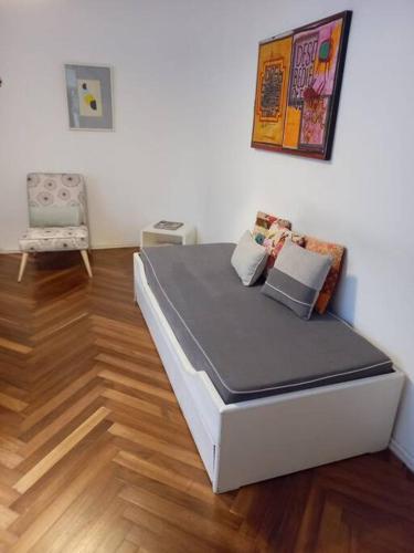 um quarto com uma cama e uma cadeira num piso de madeira em Cálido apartamento a 8 cuadras del mar y a 3 de 18 Julio Hay una gatita que vive allí em Montevidéu
