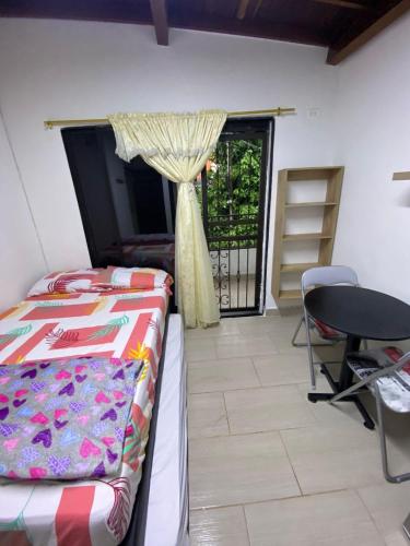 a bedroom with a bed and a table and a window at HABITACION AMOBLADA SECTOR LAURELES-ESTADIO hasta 3 personas Santorini in Medellín