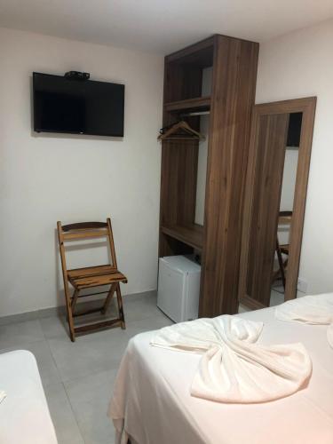 Pokój z 2 łóżkami, krzesłem i telewizorem w obiekcie POUSADA MARITIMAR w mieście Maragogi