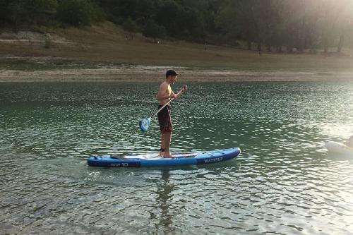 a man standing on a paddle board in the water at Casa sul lago Nonna Gio' in Colle di Tora