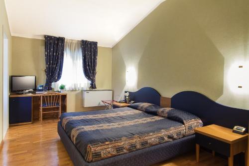 ein Schlafzimmer mit einem großen Bett und einem Schreibtisch in der Unterkunft Hotel Gambara in Gambara