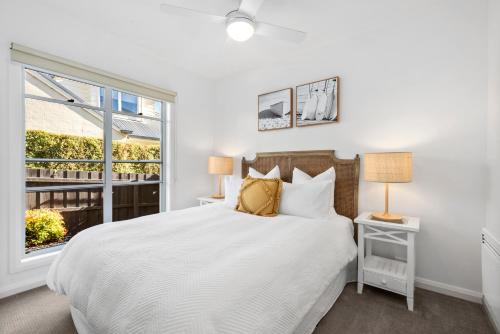 a white bedroom with a bed and a window at Villa by the Sea in Queenscliff