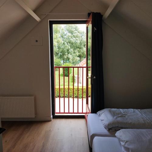 a bedroom with a door open to a balcony at Green Hills home in Ewijk