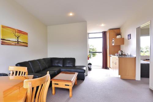 a living room with a black couch and a table at Sunset Motel in Fox Glacier