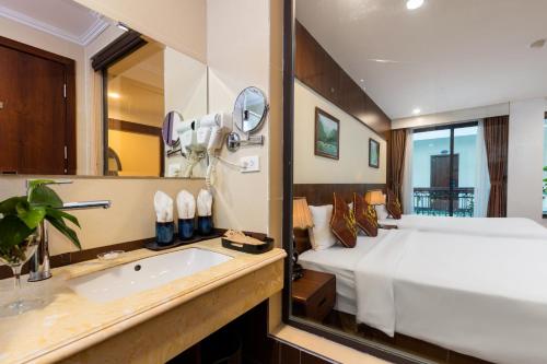a bedroom with a bed and a sink and a mirror at Liberty Hall Tam Coc Hotel & Villa in Ninh Binh