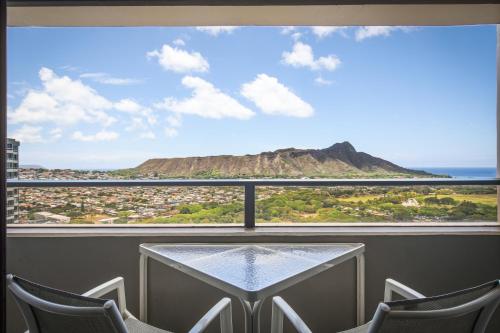 a table with chairs and a view of a mountain at Aston Waikiki Sunset in Honolulu
