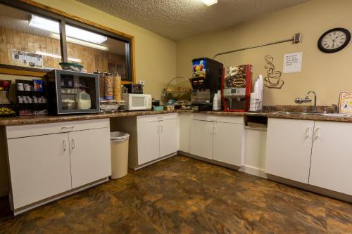 a kitchen with white cabinets and a clock on the wall at Thunderbird Lodge in Mitchell