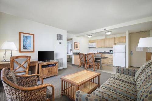 a living room with a couch and chairs and a kitchen at Aston Waikiki Sunset in Honolulu