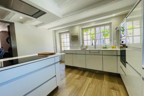 a kitchen with white cabinets and a sink at Seigneurie Les Aulnaies exceptional building with swimming pool in Fondettes