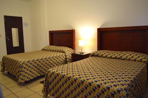 a hotel room with two beds and a lamp at Hotel San Miguel Penjamo in Pénjamo