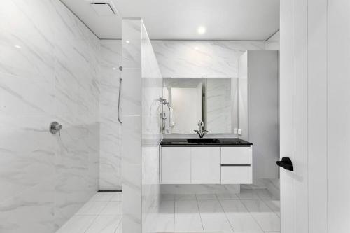 a white bathroom with a sink and a mirror at Central Tropical Oasis with Pool in Noosaville