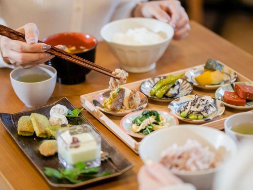 a table with plates of food and people holding chopsticks at Hotel Gracery Kyoto Sanjo in Kyoto